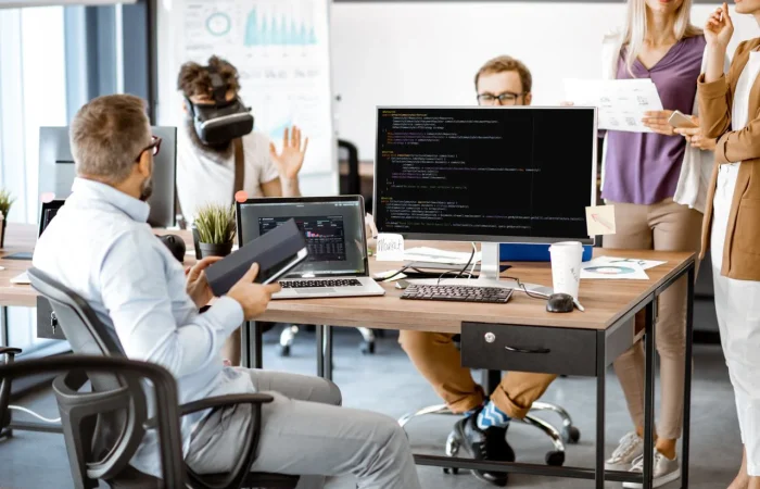 A busy office scene with colleagues collaborating, using computers, and discussing projects.